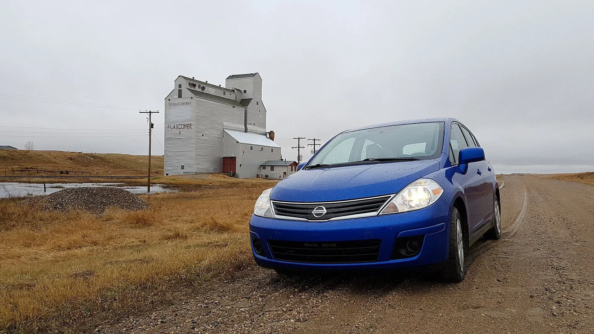 Grain elevator at Flaxcombe with a blue car on the gravel road